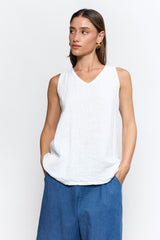 Woman wearing a white sleeveless top and blue pants on a white background