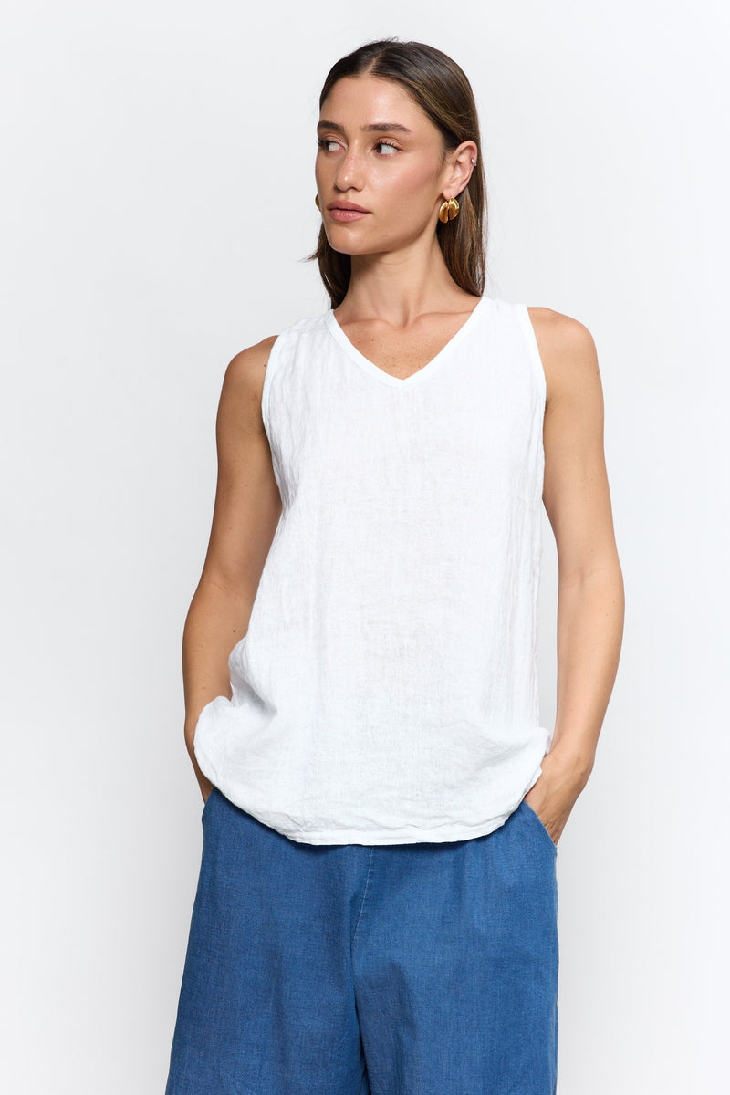 Woman wearing a white sleeveless top and blue pants on a white background